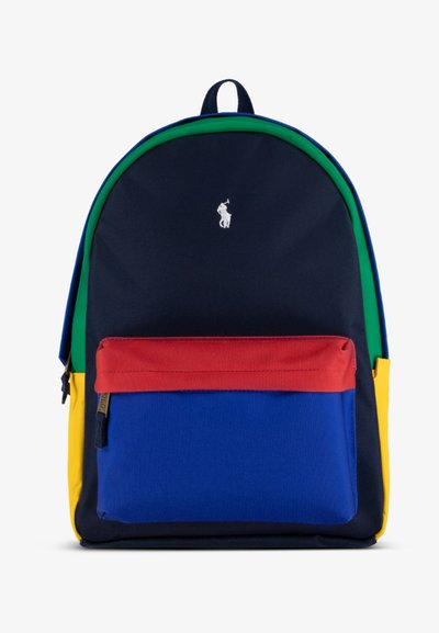 Mochila multicolor hecha de tela. Presenta paneles en azul marino, verde, azul, rojo y amarillo, con un bolsillo con cremallera en la parte frontal y detalle del logo.