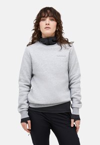 Felpa grigia con finitura testurizzata, dotata di collo nero, polsini a contrasto e un piccolo logo sul petto. Indossata con pantaloni neri.