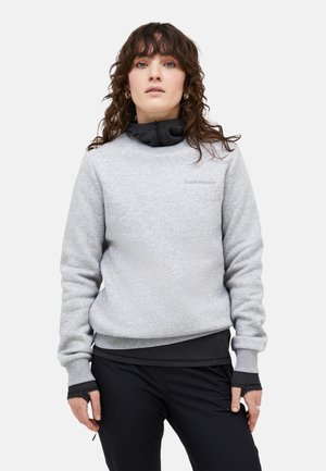 Felpa grigia con finitura testurizzata, dotata di collo nero, polsini a contrasto e un piccolo logo sul petto. Indossata con pantaloni neri.