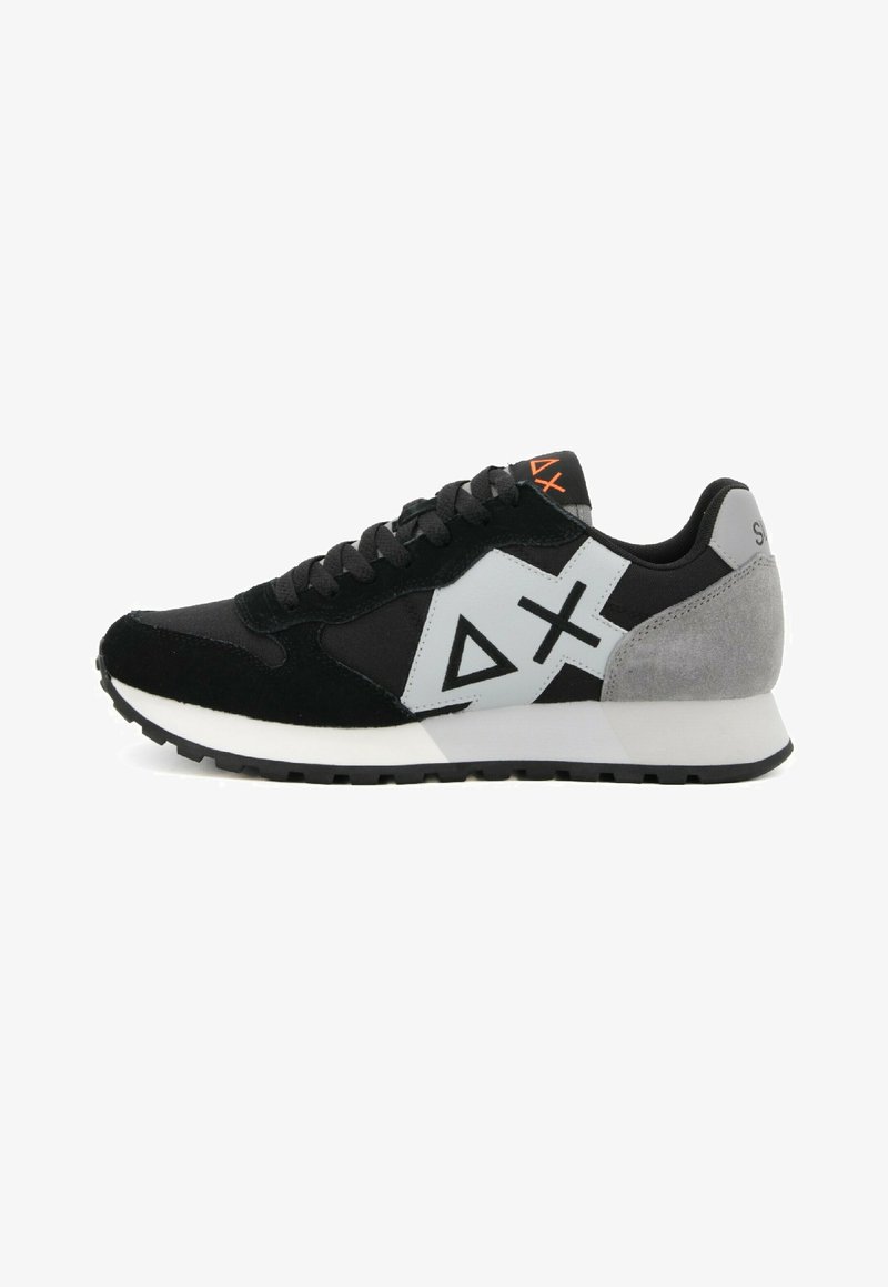 Zapatilla en negro y gris con materiales de ante y malla, que cuenta con una entresuela blanca, suela de goma y diseños de logotipos geométricos.