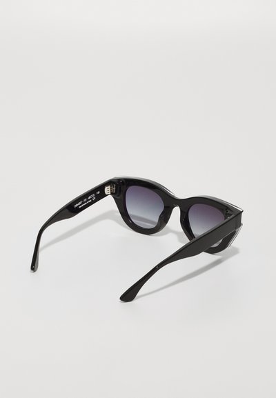 Black cat-eye sunglasses with gradient lenses, glossy plastic frame, sharp edges, metal accents on arms, and a slim profile.