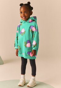 Hanorac cu glugă de culoare turcoaz, cu modele florale în roz și mov, asortat cu colanți negri și adidași albi. Material moale, croială lejeră.