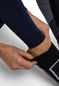 Granatowe legginsy sportowe o texturowanym wykończeniu, w zestawieniu z czarną skarpetą z kolorowym wzorem, dopasowywaną wokół kostki.