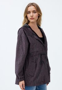 Donkerpaarse regenjas met een luipaardprint, elastische manchetten, een taille met trekkoord en een capuchon gevoerd met een contrasterende textuur.