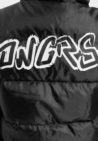 Black puffer jacket with quilted texture; features large white graffiti-style text "ONGRS" on the back; glossy finish.