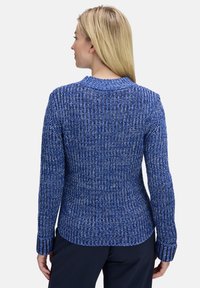 Pull en tricot bleu avec un motif texturé, manches longues, poignets côtelés et un col rond. Le tissu semble doux et chaud.