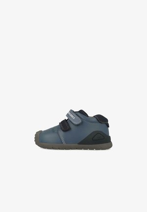 Zapato infantil azul con suela de goma, que cuenta con dos correas de velcro ajustables y un material superior suave, punta redondeada y detalles en las costuras.