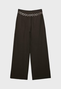 Pantalon noir à jambes larges avec taille haute et ceinture décorative en chaîne argentée composée d'anneaux circulaires liés.