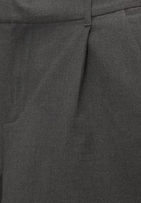 Pantalon gris foncé sur mesure en tissu lisse avec une texture subtile, doté de plis sur le devant et de poches latérales pour la fonctionnalité.