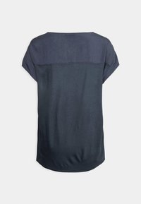 Top corto blu scuro a maniche corte con un pannello orizzontale blu chiaro sul retro, texture liscia, scollatura rotonda e vestibilità rilassata.