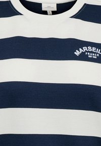 T-shirt à rayures bleu marine et blanches en coton doux. Présente un col rond et "MARSEILLE FRANCE EST 1952" brodé en blanc.