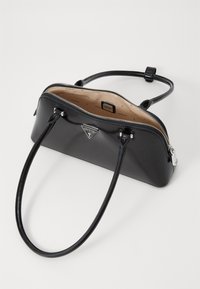 Borsa in pelle lucida nera con una forma strutturata, chiusura con zip, manici doppi e una placca con logo sulla parte anteriore. Fodera interna liscia.