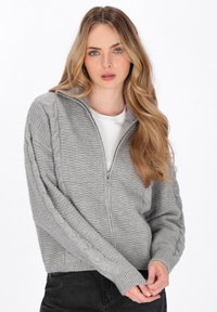 Cardigan gri cu fermoar, realizat dintr-un material tricotat texturat, având accente din cablu pe mâneci și manșete și tiv din tricot rib. 