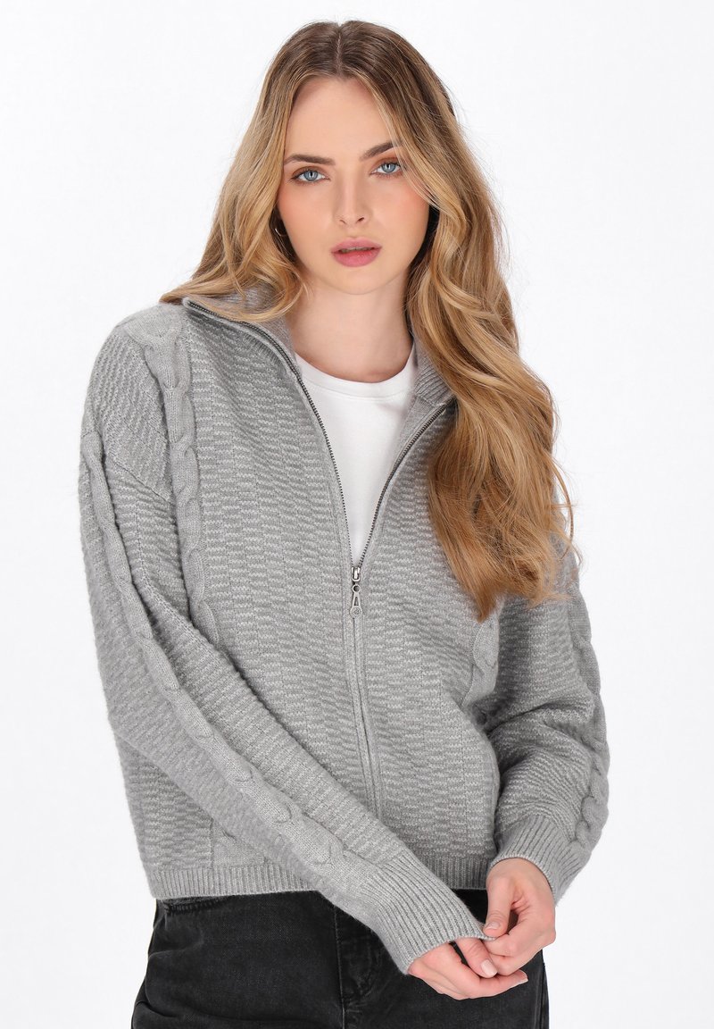 Cardigan gri cu fermoar, realizat dintr-un material tricotat texturat, având accente din cablu pe mâneci și manșete și tiv din tricot rib. 