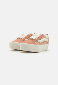 Pink and beige suede sneakers with white laces, rounded toe, platform sole, and contrasting side stripe design.