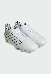 Botas de fútbol blancas con parte superior de cuero texturizado, rayas de acento verde y negro, y detalles de marca negros en la lengua y los lados.