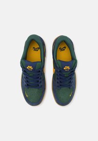 Para buty Nike SB Force 58 w kolorze zielonym i granatowym z żółtymi akcentami, widziane z góry na białym tle.