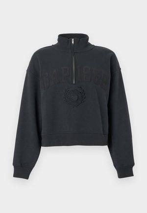 Μαύρο cropped φούτερ με γιακά μισού φερμουάρ, μακριά μανίκια και ανάγλυφο κείμενο και έμβλημα "GAP 1969" μπροστά.