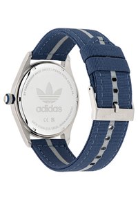 Montre Adidas avec un boîtier en acier inoxydable, bracelet en tissu tissé bleu marine avec des rayures gris clair et boucle en argent. Logo gravé au dos.