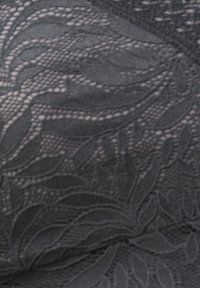 Black lace fabric with intricate floral and leaf patterns creating a textured, semi-transparent surface.