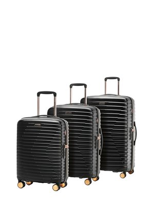 Trois valises rigides noires avec poignées télescopiques et quatre roues dorées, disposées de la plus petite à la plus grande taille.