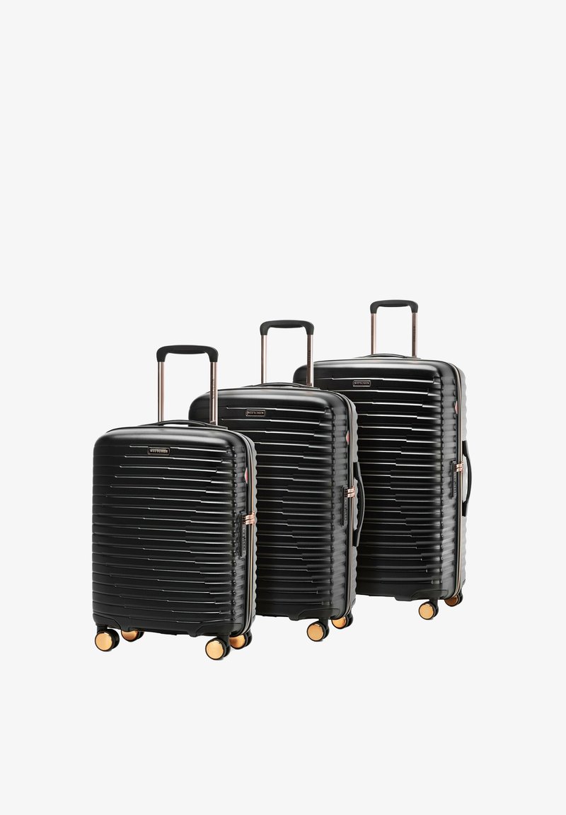 Tres maletas negras de carcasa dura con asas telescópicas y cuatro ruedas doradas, ordenadas de menor a mayor tamaño.