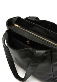 Black leather tote bag with dual handles, featuring a zippered compartment lined with fabric and gold-toned hardware details.