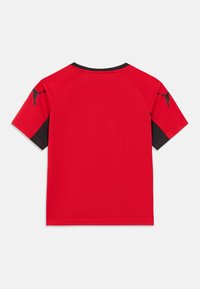 Κόκκινο αθλητικό μπλουζάκι με μαύρες λεπτομέρειες, κοντά μανίκια ράγκλαν και λεία υφή. Διαθέτει μικρό λογότυπο στον αριστερό ώμο.