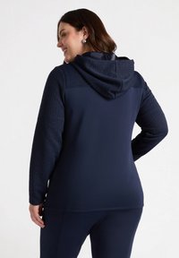 Felpa blu navy con motivo testurizzato sulle maniche, dotata di cappuccio e vestibilità comoda. Tessuto morbido con maniche lunghe e tasca a marsupio.