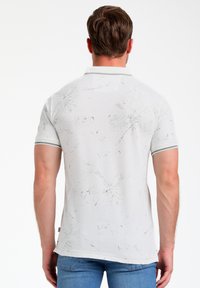 Polo bianco con un motivo testurizzato e dettagli grigi, maniche corte e un design minimalista con una leggera lucentezza.