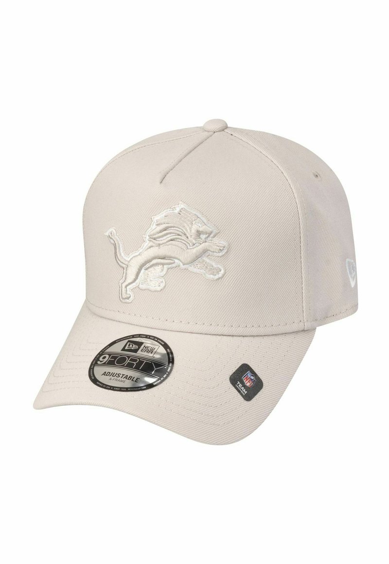 Verstellbare beige Kappe mit strukturiertem Oberflächen, versehen mit einem weißen gestickten Löwenlogo auf der Vorderseite und einem schwarzen runden Etikett auf dem Schirm.