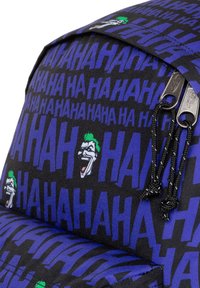 Mochila con tela negra que presenta un gran texto azul "HA" y gráficos del Joker. Cremalleras con cuerdas negras, textura suave y forma estructurada.