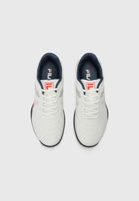 White athletic shoes with navy accents, smooth textured upper, lace-up design, and red logo. Features horizontal lines across the sides.