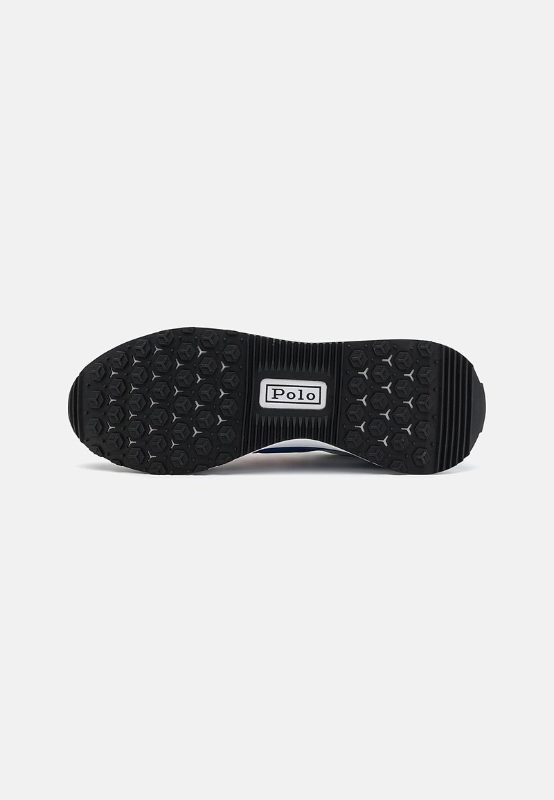 Suela de zapato de goma negra con un patrón de agarre hexagonal, que presenta una etiqueta blanca central con el texto "Polo". Diseño texturizado y ligeramente contorneado.