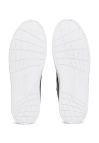 Weiße Gummisohlen mit einem strukturierten Grip-Muster; verfügen über eine strukturierte Außensohle und eine geprägte Markenkennzeichnung an der Seite.