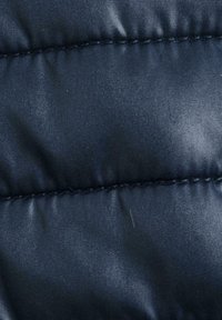 Tissu matelassé bleu marine avec une texture lisse et un subtil éclat, présentant des lignes cousues et une apparence douce et rembourrée.