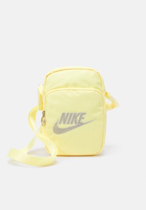 Petit sac bandoulière rectangulaire jaune Nike avec poche avant zippée et bandoulière réglable.