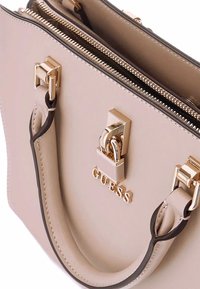 Bolso beige hecho de material sintético. Presenta un cierre de doble cremallera, herrajes en tono dorado y acentos en negro en las asas.