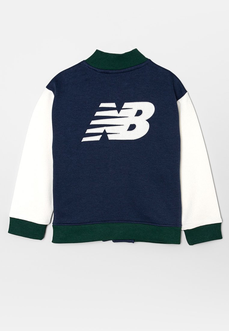 Veste bleu marine avec des manches blanches, col et poignets verts, présentant un logo New Balance blanc au dos.