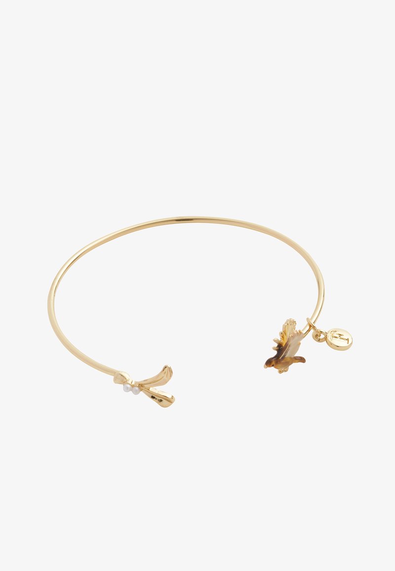 Pulsera de color dorado con un diseño liso y redondeado. Presenta un charm de plátano y un pequeño acento de flor, con dos detalles de perlas blancas.