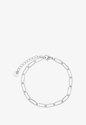 Bracelet en chaîne argentée avec des maillons allongés, un fermoir en homard et une chaîne réglable avec une petite étiquette circulaire.