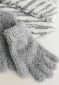 Grå, fluffiga handskar med en strukturerad yta och sömlös design. Mjuka och mysiga, placerade bredvid en randig vit och grå halsduk.