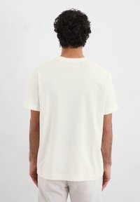Short-sleeve t-shirt in off-white cotton. Features a classic crew neck and relaxed fit; smooth texture and minimalistic design.