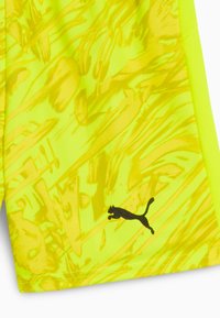 Pantalones cortos deportivos de color amarillo neón con patrones abstractos y un logo negro de Puma. Fabricados en un material sintético ligero y texturizado.