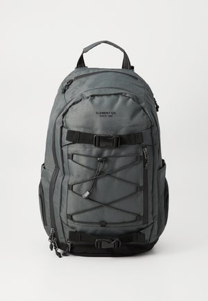 Grijze stoffen rugzak met verstelbare schouderbanden, een handvat aan de bovenkant, meerdere met rits afgesloten vakken en een elastisch koorddetail op de voorkant.