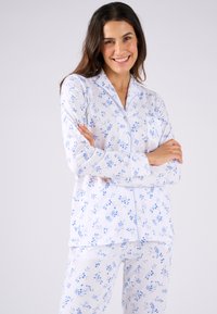 Ensemble de pyjama blanc avec imprimé floral bleu, comprenant une chemise à boutons avec col et manches longues, assortie à un pantalon.