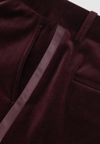 Bordo plišane hlače s glatkom teksturom, ravnim prednjim dijelom sa satenskim obrubom i jednim stražnjim džepom.