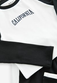 Czarny i biały long-sleeve top z prążkowaną fakturą, kontrastującymi rękawami i wyszytym napisem "CALIFORNIA" w granatowym kolorze na klatce piersiowej.