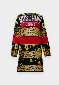 Juodas megztinis su vertikaliomis raudonomis ir auksinėmis juostelėmis, gėlėmis geltonos ir žalios spalvos, ir tekstu "MOSCHINO JEANS."