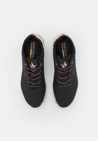 Scarpe sportive nere con tomaia in mesh, punta rotonda e lacci decorativi. Presentano dettagli in bronzo e solette imbottite per il comfort.